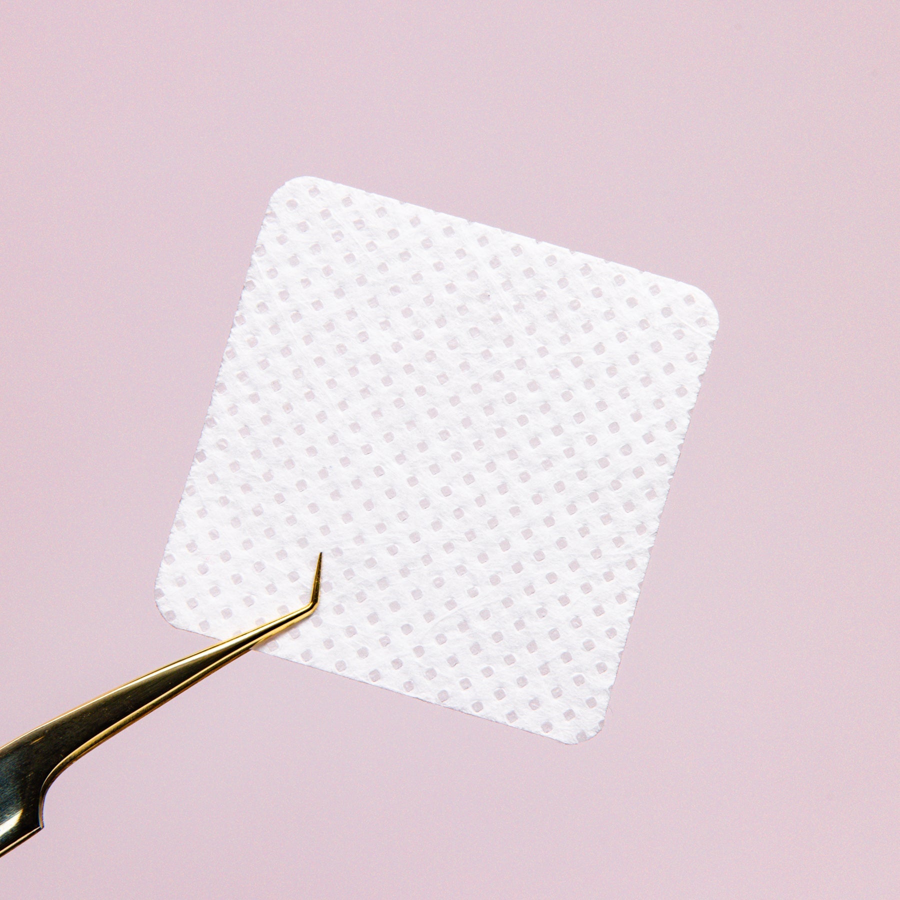 Adhesive Nozzle Wipe Close Up over a pink background.
