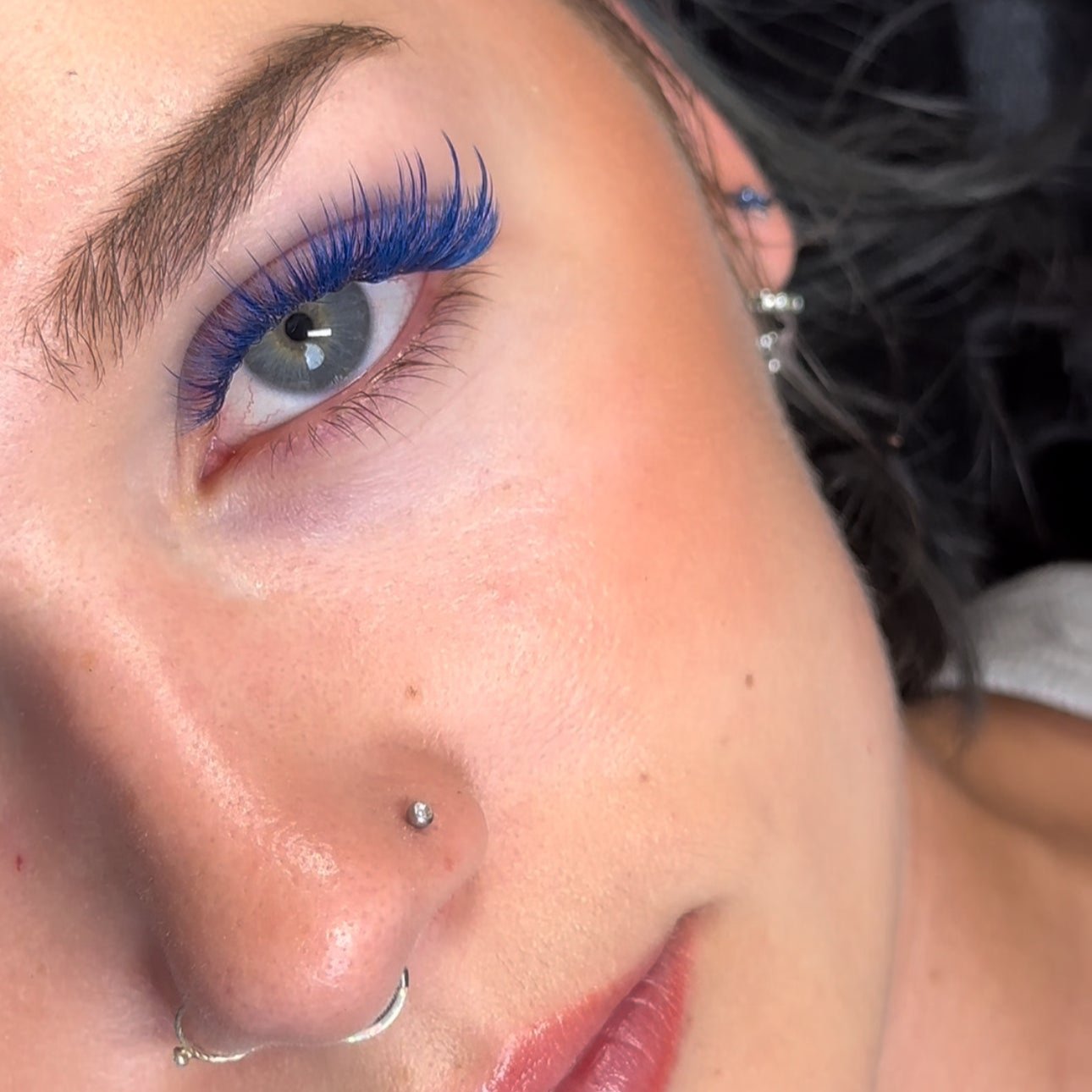 Close-up of a model with blue wispy eyelash extensions, showcasing detailed lash application.