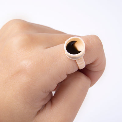 A hand wearing a Silicon Glue Ring filled with a glue on a white background.