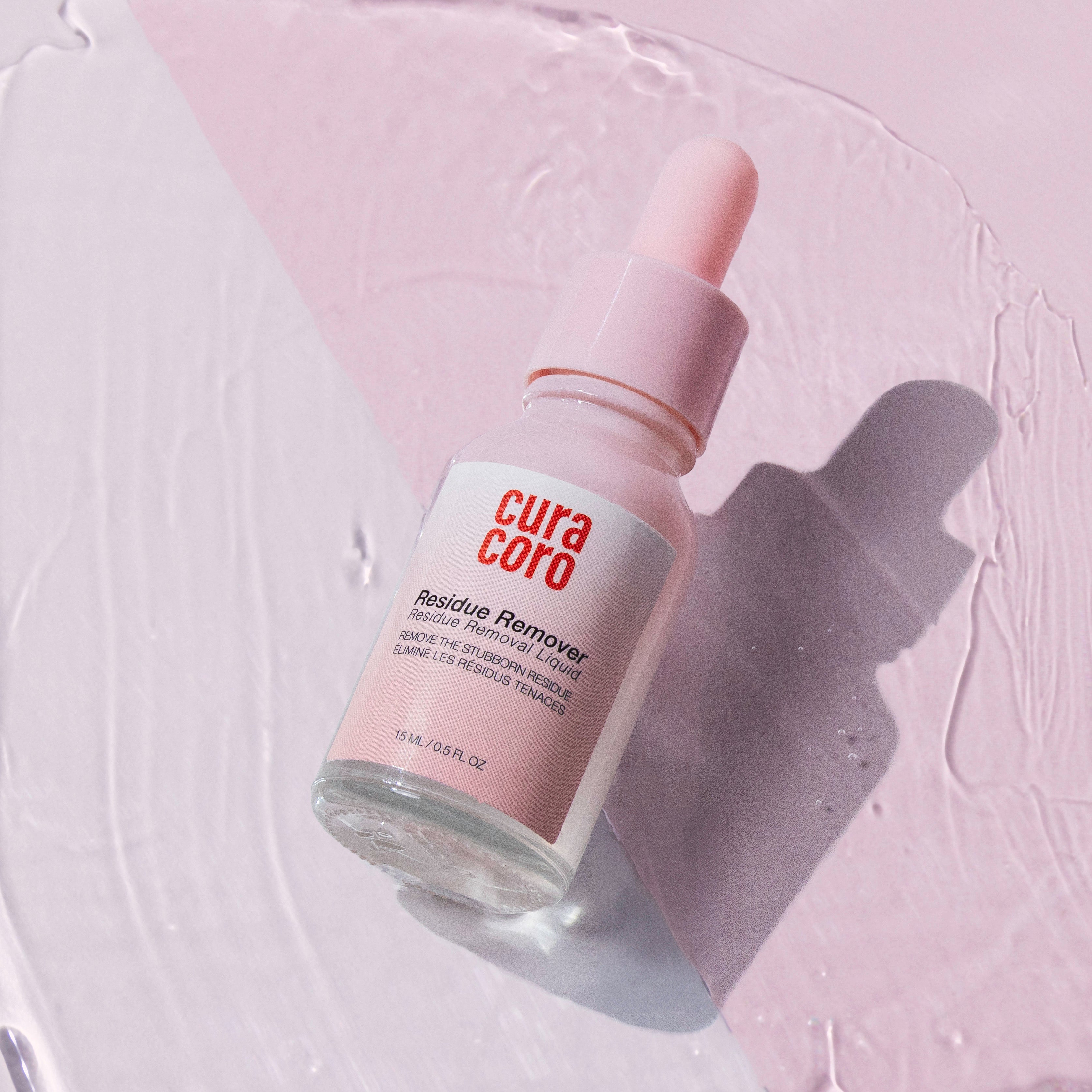 Curacoro Residue Remover in a pink dropper bottle, placed on a textured pink surface, with shadow detailing.