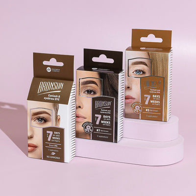 Three packages of lash and brow dye on a pink background