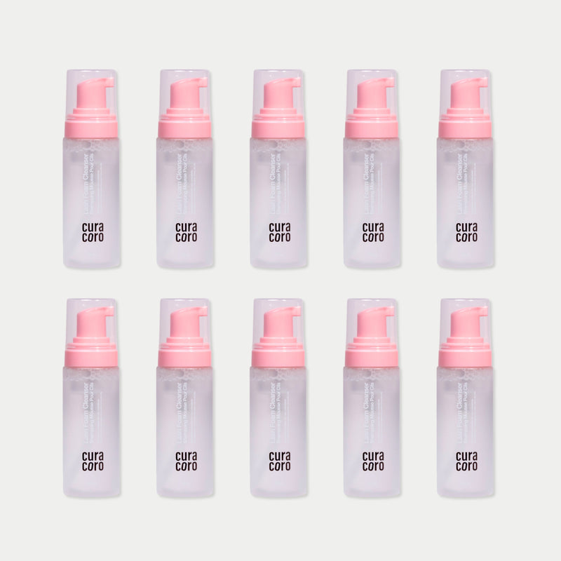 Ten Curacoro Lash Foam Cleansers arranged in a grid pattern on a light background, featuring pink pumps.