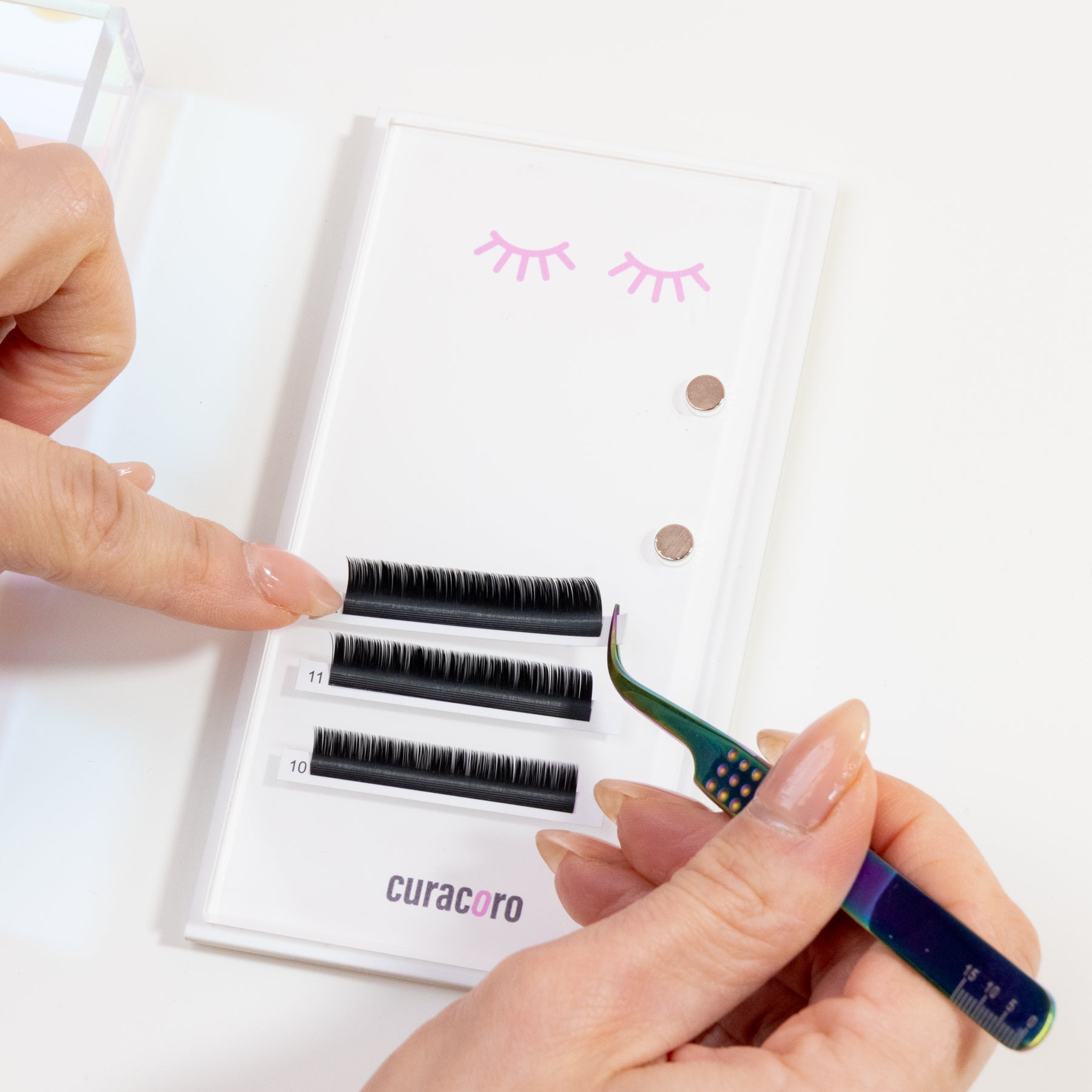 Curacoro magnetic lash tile with labeled lash strips and iridescent tweezer, designed for precise lash application.