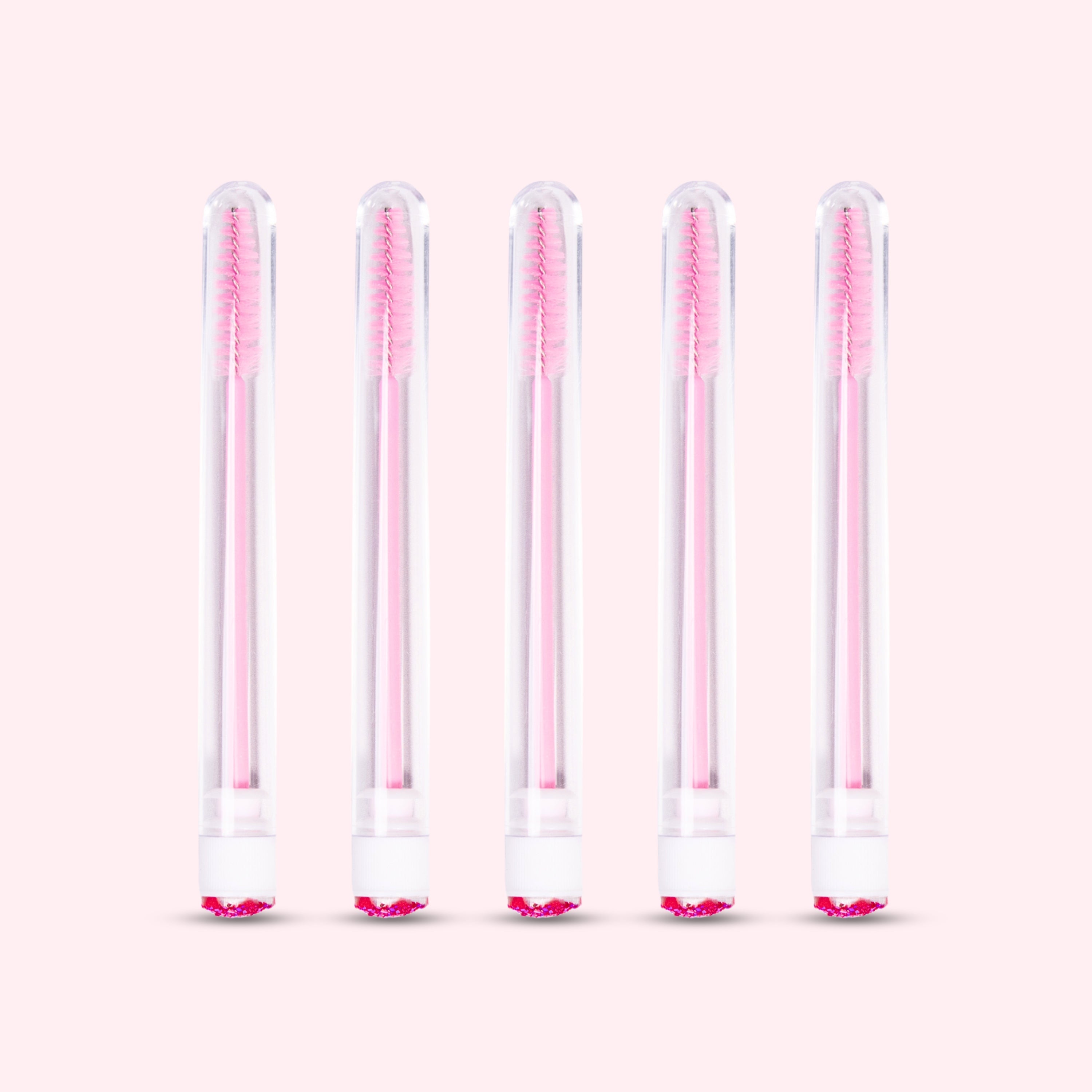 Five pcs Mascara Brushes with Tubes over a light pink background. 