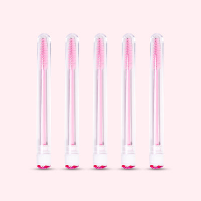 Five pcs Mascara Brushes with Tubes over a light pink background. 