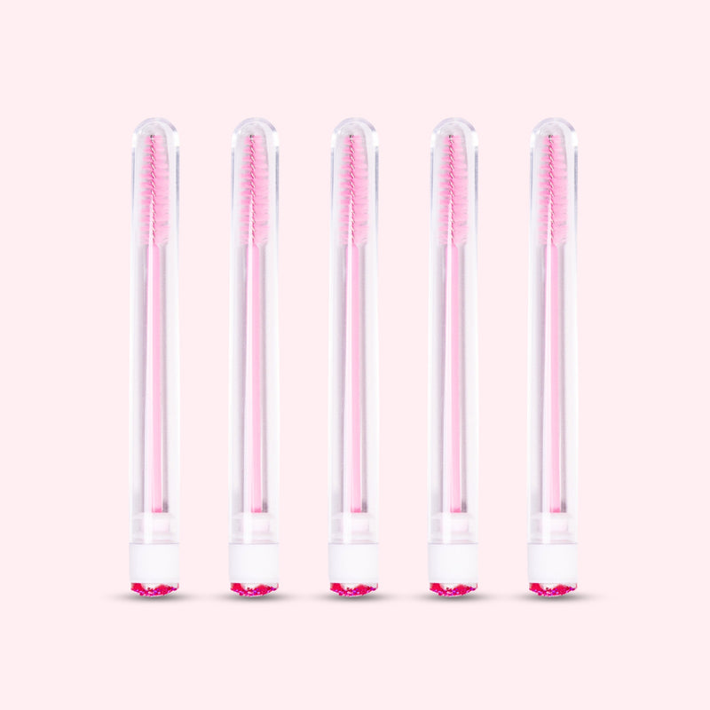 Five pcs Mascara Brushes with Tubes over a light pink background. 