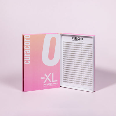 Curacoro XL Promade Fans for eyelash extensions, featuring a sleek pink and white box with an open tray showcasing narrow, slim lash fans arranged neatly.