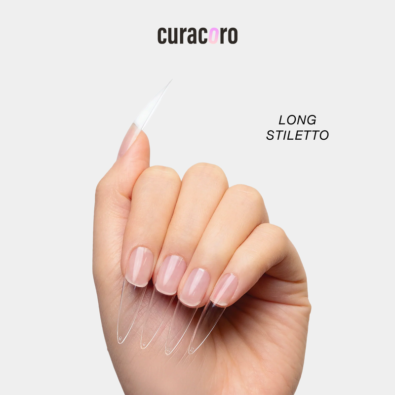 Curacoro long stiletto soft gel nail tips applied on a model’s hand, clear extensions with a sharp tapered shape