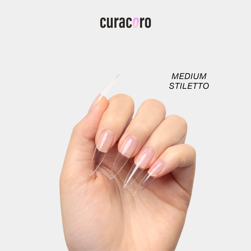 Curacoro medium stiletto soft gel nail tips applied on a model’s hand, clear extensions with a sharp tapered shape