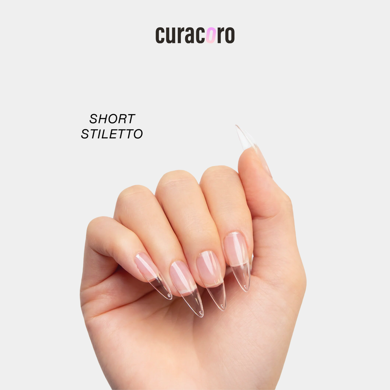 Curacoro short stiletto soft gel nail tips applied on a model’s hand, clear extensions with a sharp tapered shape