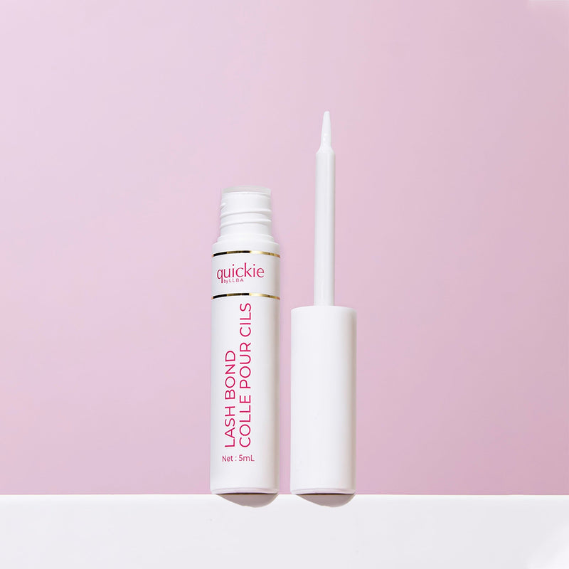 An open tube of lash bond with a white applicator brush, positioned upright on a light purple background.