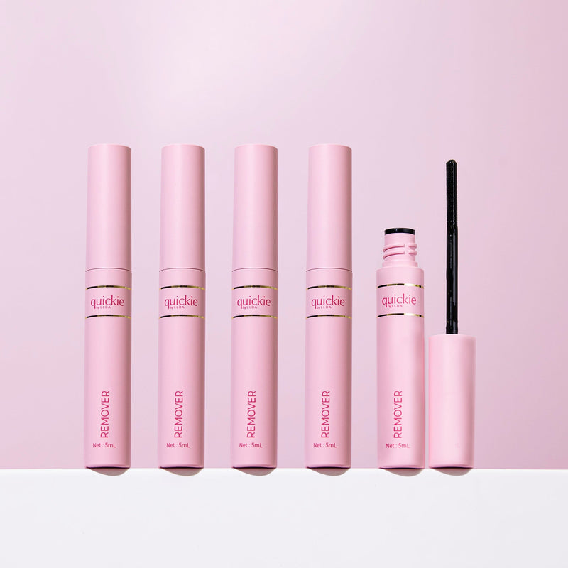 A lineup of five Quickie by LLBA Remover tubes, with one open to reveal the wand applicator, displayed against a light pink background.