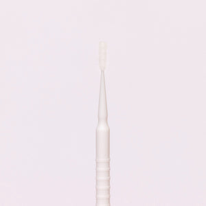 White disposable micro applicator with a fine brush tip, ideal for precise application of beauty products.