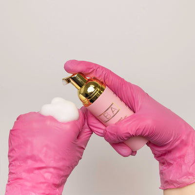 Lash bath being applied on model's hand over a pink glove.