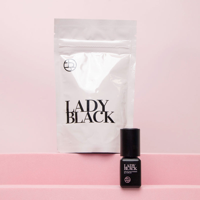 Lady Black glue for eyelash extensions with bottle and packaging displayed in the background.