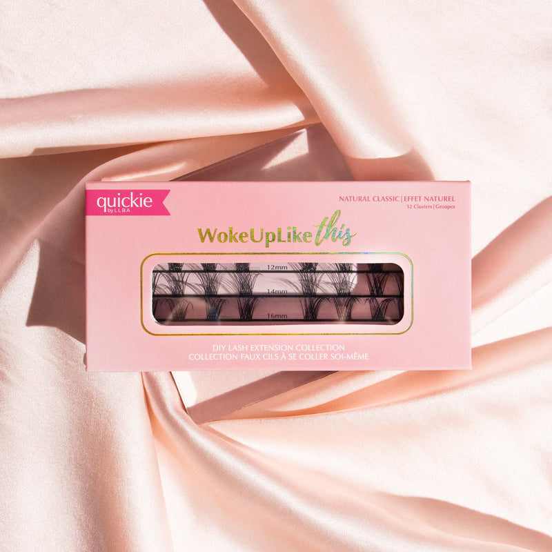 Pink lash extension kit box with transparent window showing three rows of lash clusters in different lengths, placed on soft, peach-colored fabric.