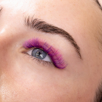 Close-up view of vibrant pink eyelash extensions applied flawlessly, enhancing the natural beauty of the eye.