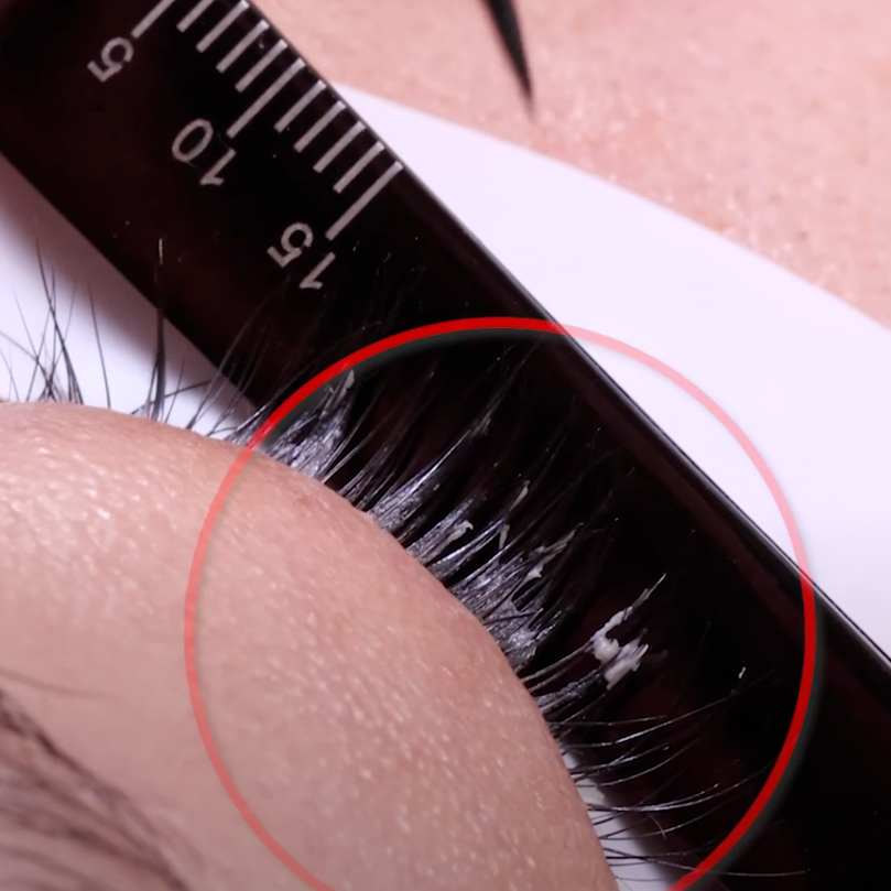 Close-up of eyelash being measured with a ruler, highlighting a red circle around glow on the lash.