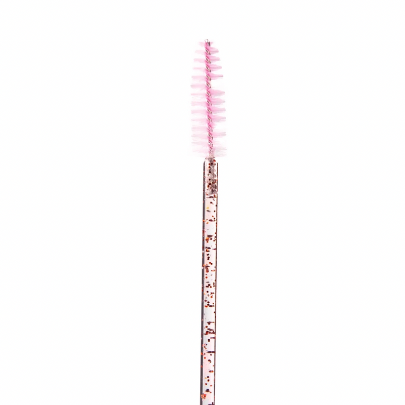 Pink lash spoolie brush with a transparent handle featuring gold glitter detailing on a white background.