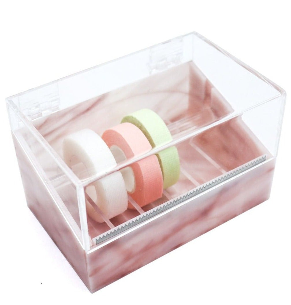 Acrylic tape dispenser with a pink marble base, featuring a clear lid and built-in serrated cutter, holding three rolls of medical-grade tape in white, pink, and green.