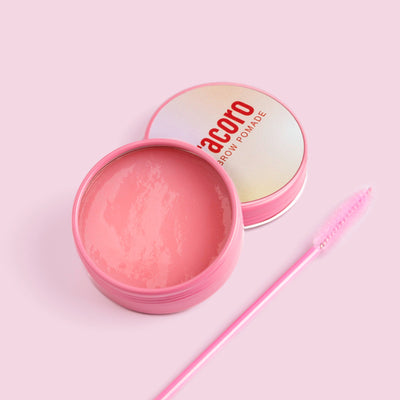 Curacoro Chic Brow Pomade with open case in front of a pink background.