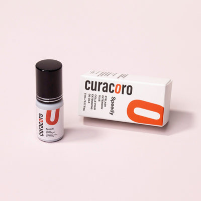 Curacoro Speedy Eyelash Extension Glue, 5 mL, in sleek white packaging with a black cap, designed for fast drying and strong retention.