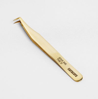 Give Me The D Tweezer Gold over a light background. 