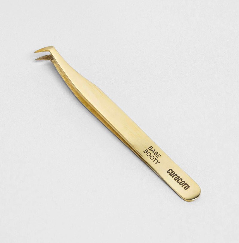 Babe Booty Tweezer Gold over a white background. 