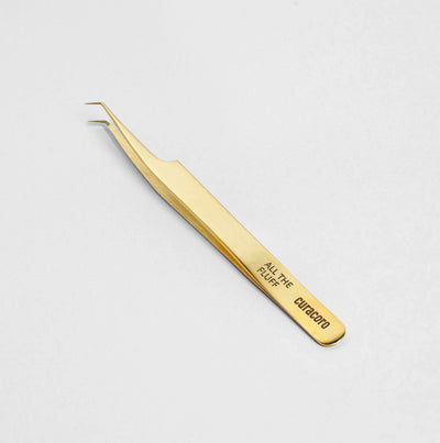 All The Fluff Tweezer Gold over a light background. 