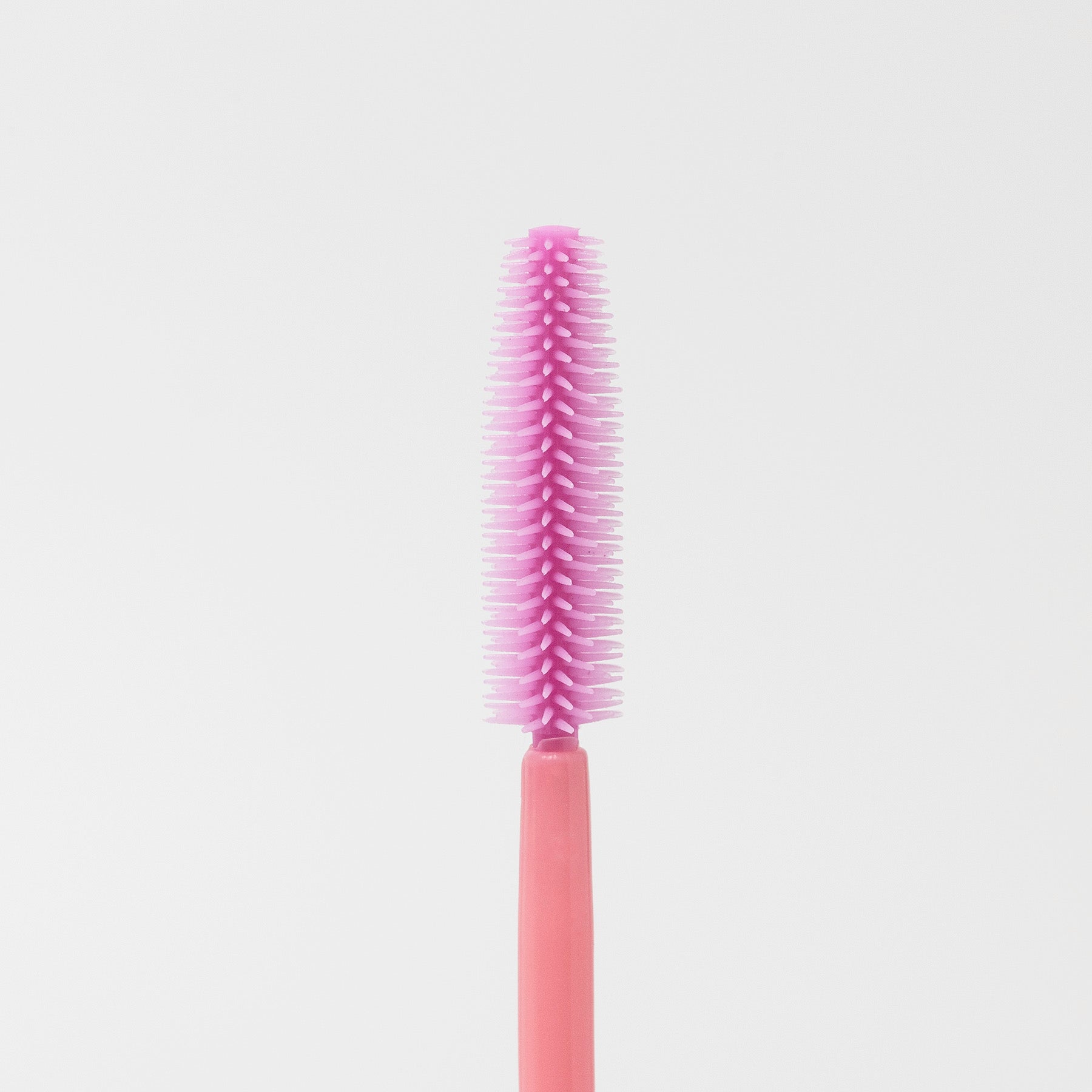 Image of the texture of a disposable pink silicon brush wands for eyelashes and brows.