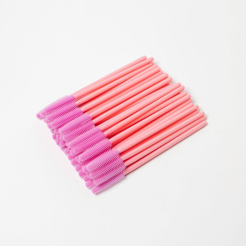 Image of disposable pink silicon brush wands for eyelashes and brows in a white background.