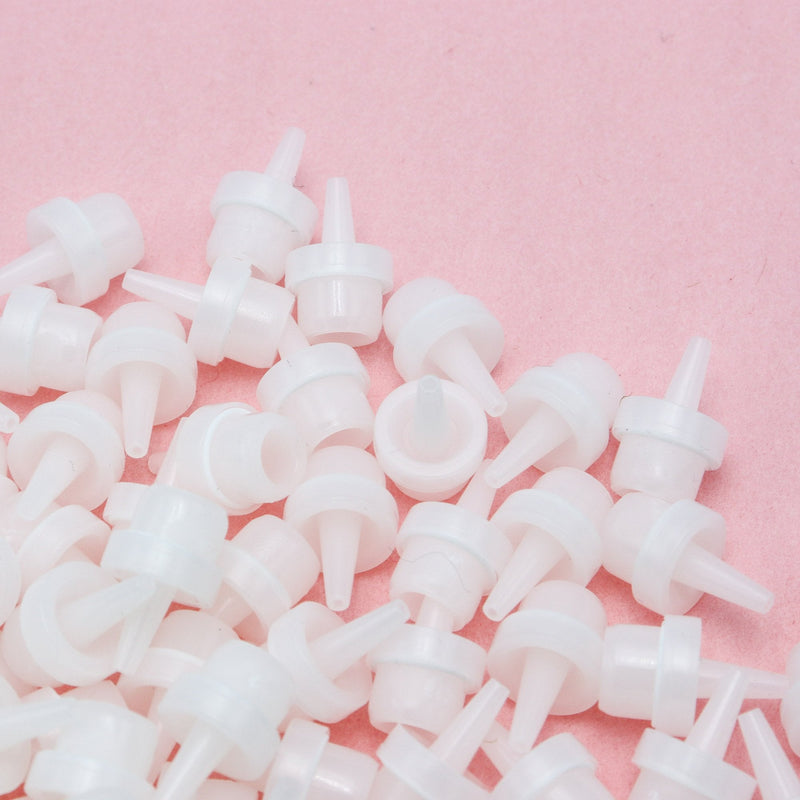 Adhesive nozzles for eyelash extension adhesive in front of a pink background.