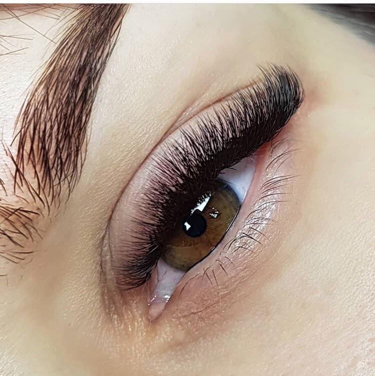 Close-up of an eye with full, voluminous eyelash extensions, showcasing professional lash application.