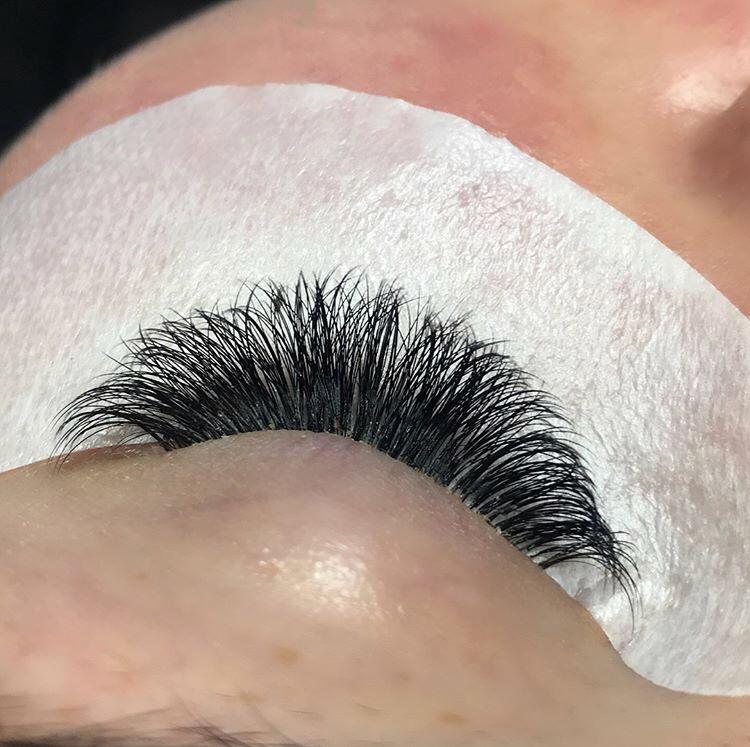 Close-up of an eye with full, voluminous eyelash extensions, showcasing professional lash application.