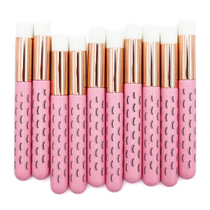 Ten pink wooden cleansing brushes over a white background