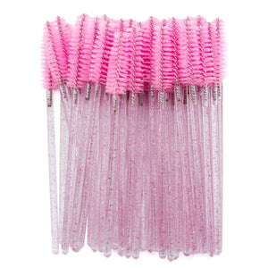 Pink disposable mascara wands with glitter handles, arranged in a bundle on a white background