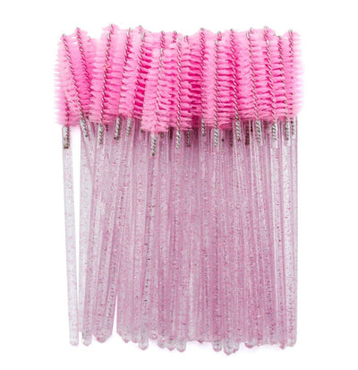 Pink disposable mascara wands with glitter handles, arranged in a bundle on a white background